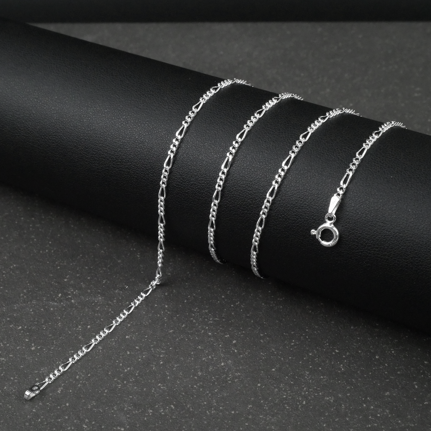 Silver fine figaro chain necklace on a dark surface