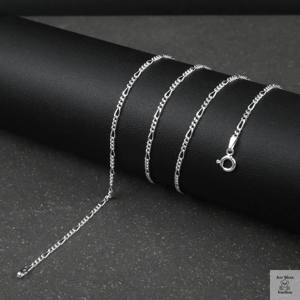 Silver fine figaro chain necklace on a dark surface