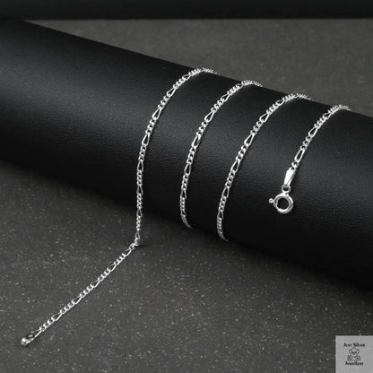 Silver fine figaro chain necklace on a dark surface