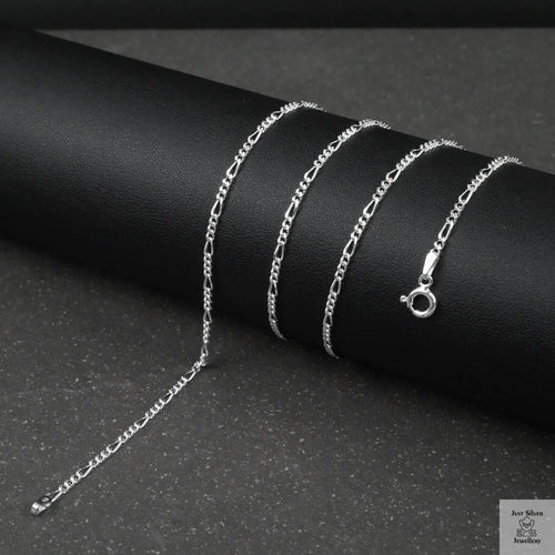 Silver fine figaro chain necklace on a dark surface