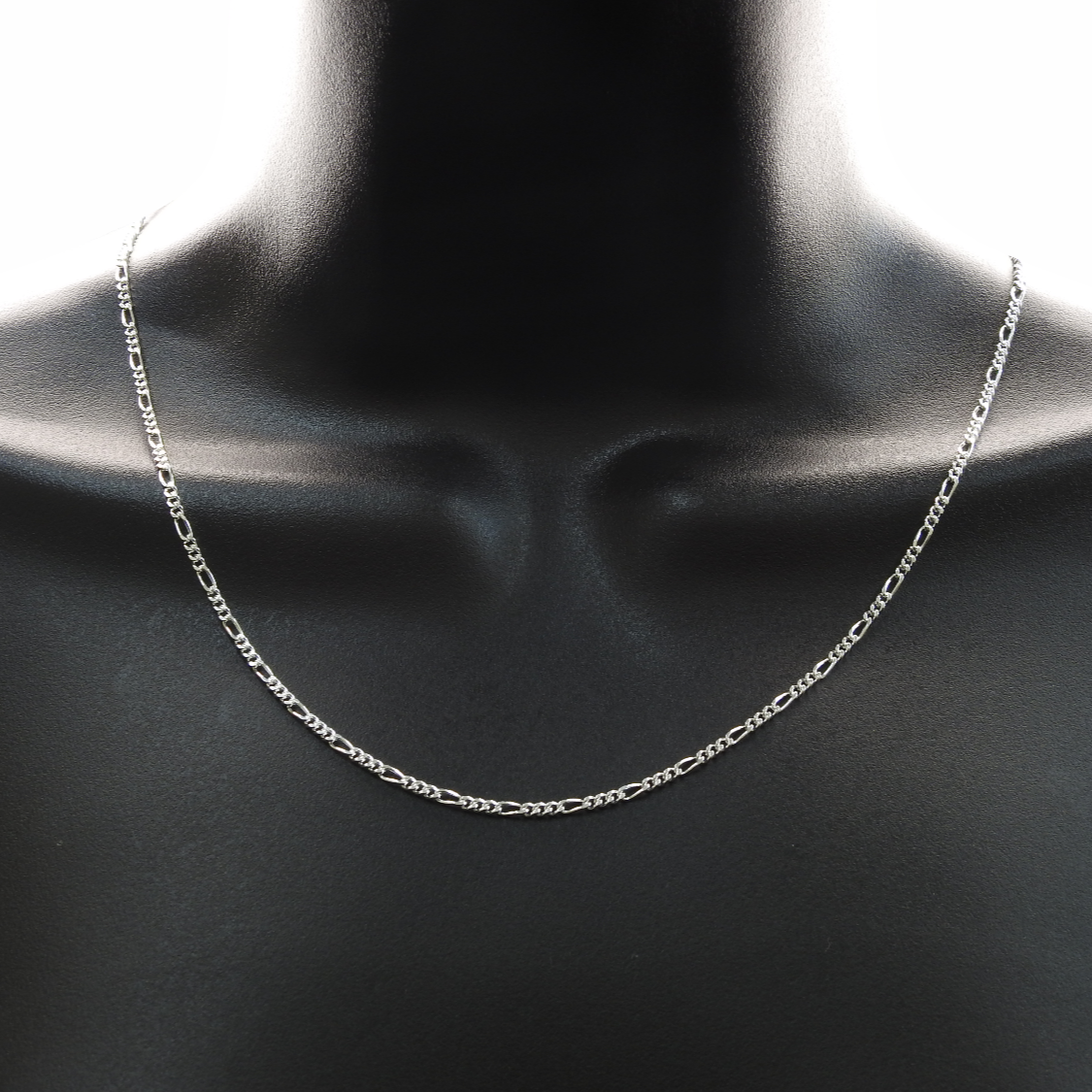 Silver chain necklace on a mannequin neck against a dark background