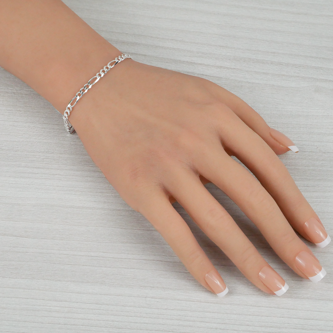 Silver bracelet on a hand with a light background