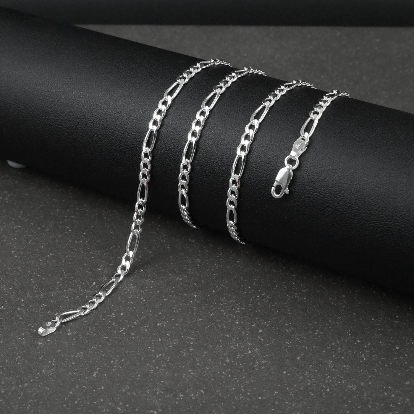 Silver figaro chain on a dark surface