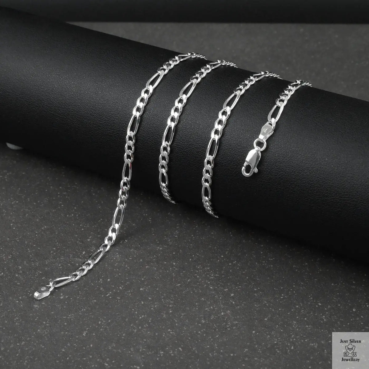 Silver figaro chain on a dark surface