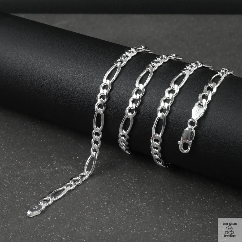 Silver figaro chain on a dark surface