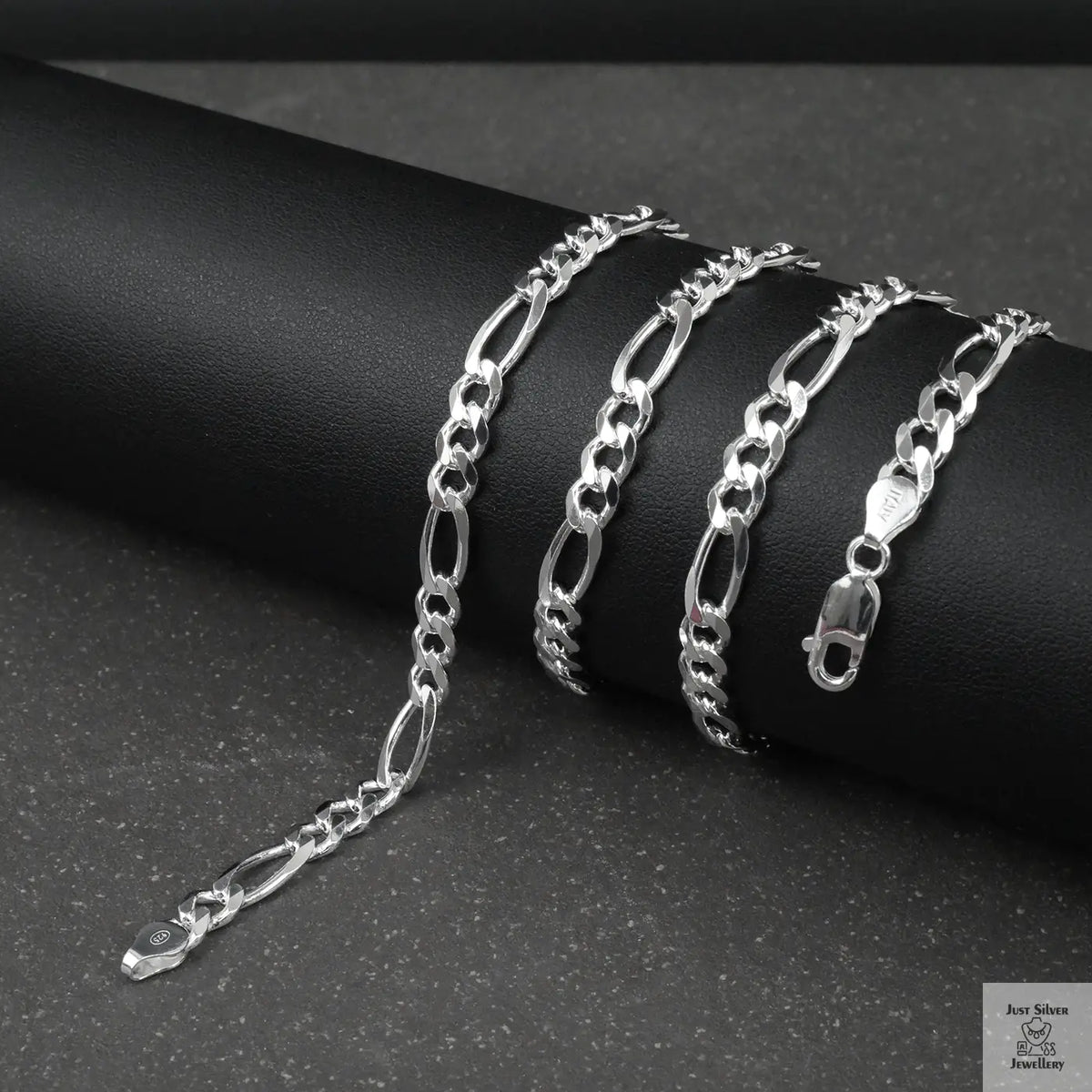 Silver figaro chain on a dark surface