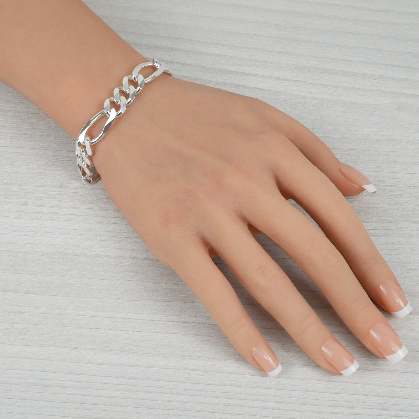 Silver chain bracelet on a hand against a neutral background