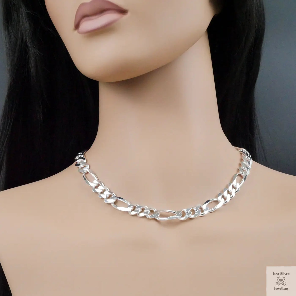 Silver figaro chain necklace on a mannequin with a plain background