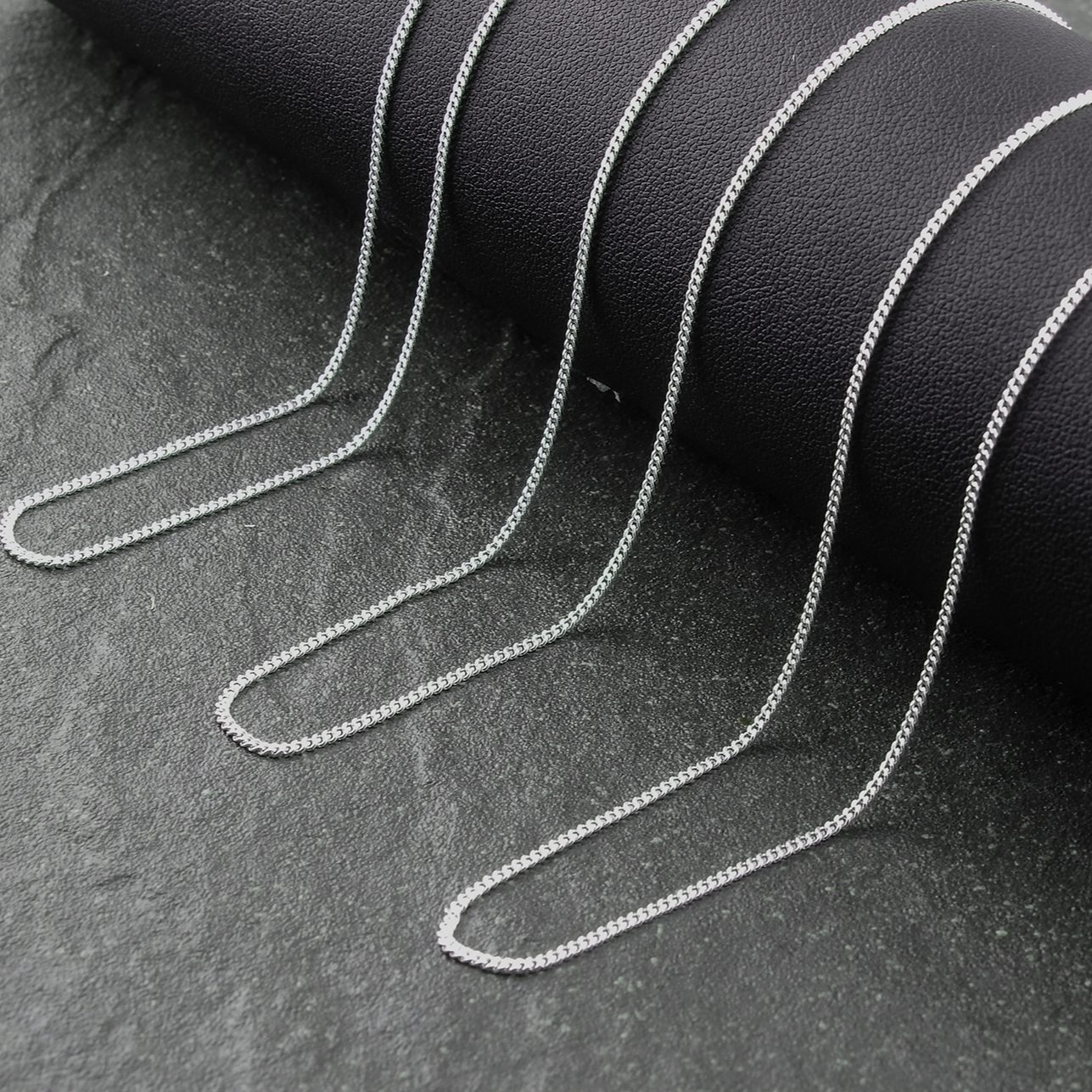 Silver chain on a dark textured surface