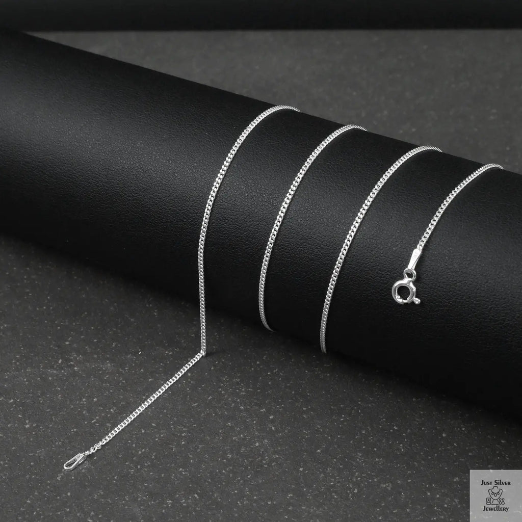 Silver fine curb chain necklace on a black textured surface