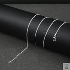 Silver fine curb chain necklace on a black textured surface