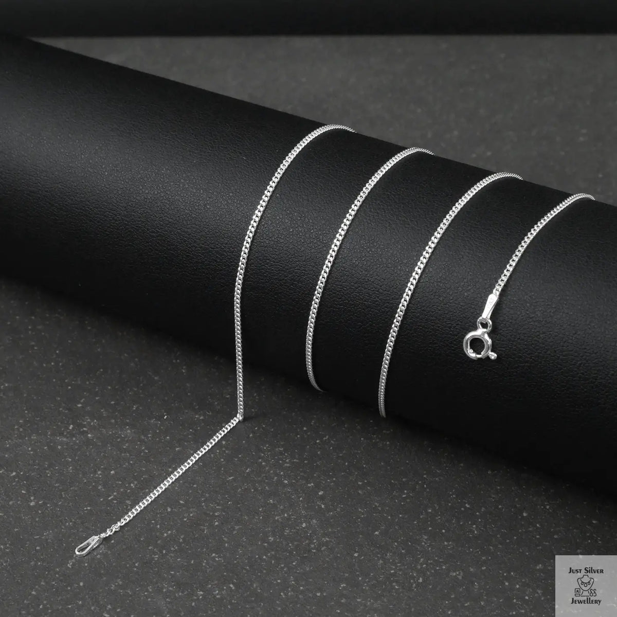 Silver fine curb chain necklace on a black textured surface