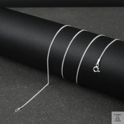 Silver fine curb chain necklace on a black textured surface