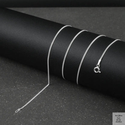 Silver fine curb chain necklace on a black textured surface