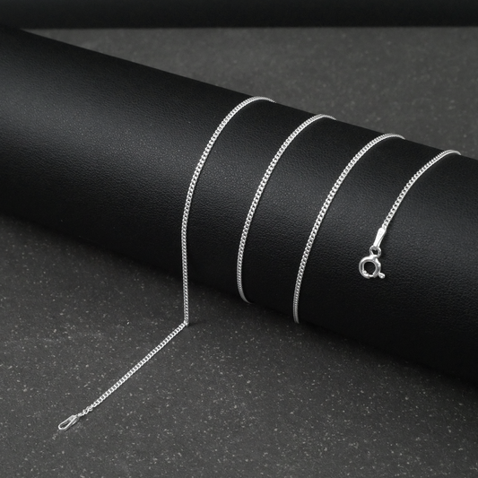 Silver fine curb chain necklace on a black textured surface
