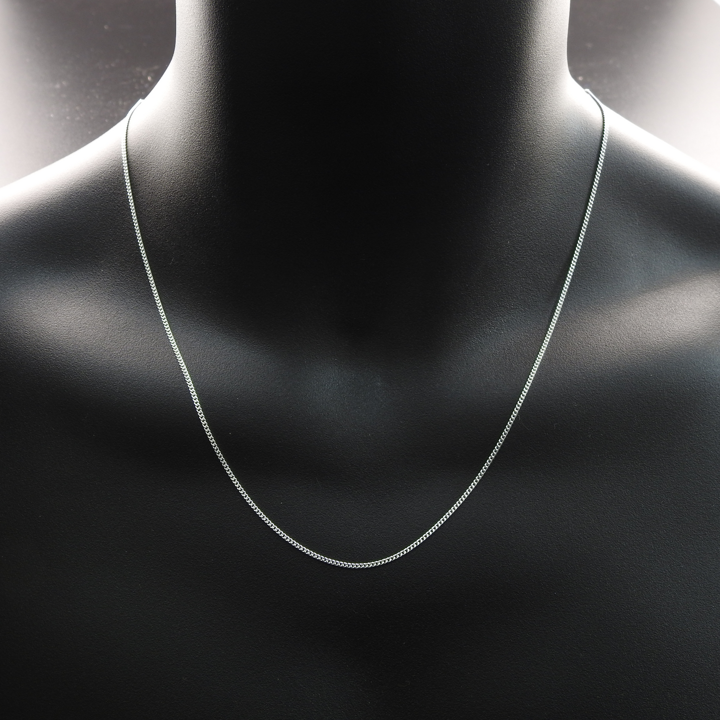 Silver necklace on a black mannequin bust.