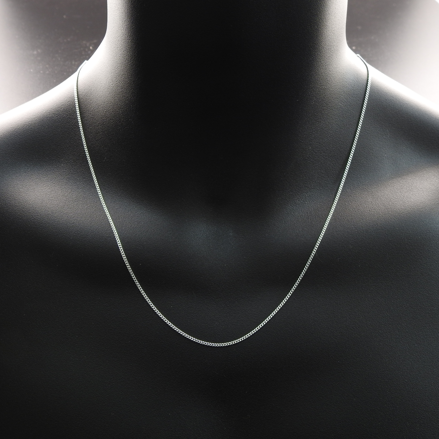 Silver necklace on a black mannequin bust.