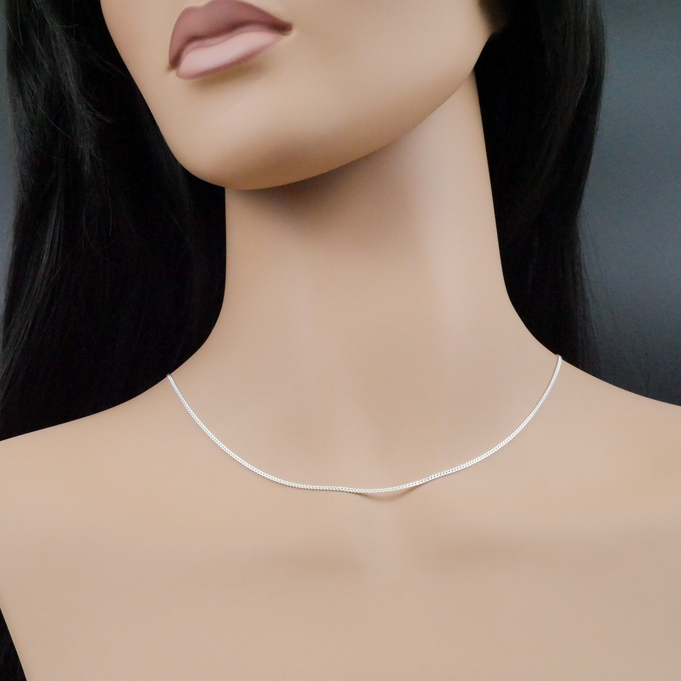 Mannequin wearing a silver necklace against a dark background