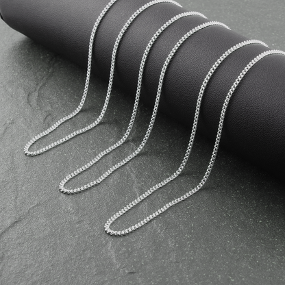 Silver chain necklace on a black cylindrical object against a gray background