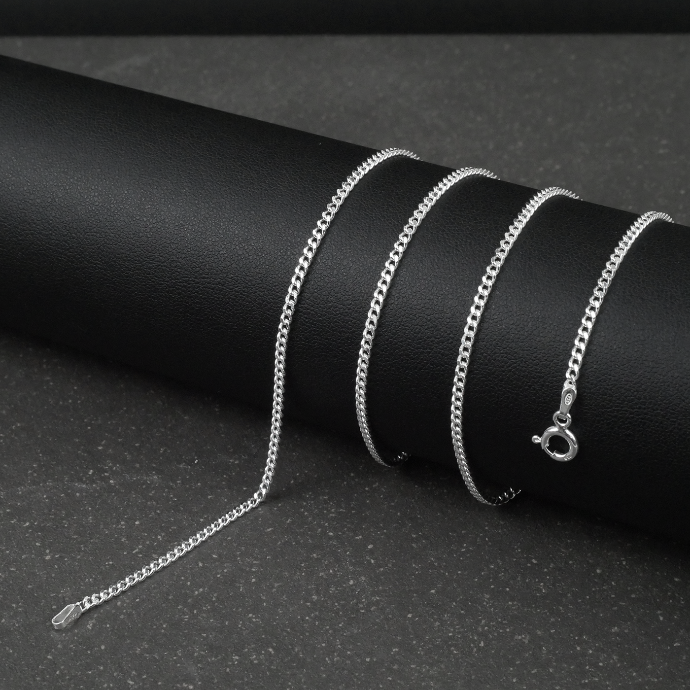 Silver fine curb chain necklace on a black cylindrical object