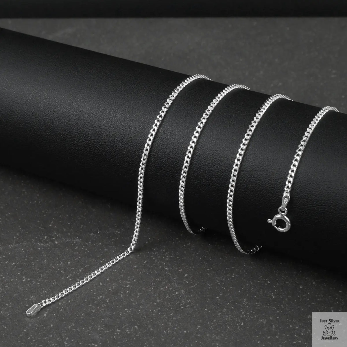 Silver fine curb chain necklace on a black cylindrical object