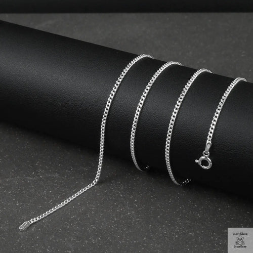 Silver fine curb chain necklace on a black cylindrical object