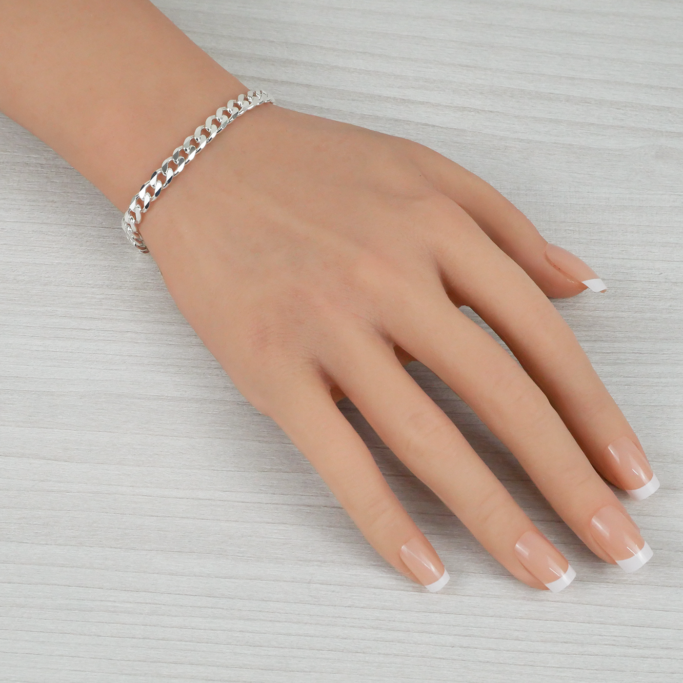 Hand wearing a silver bracelet on a light gray background