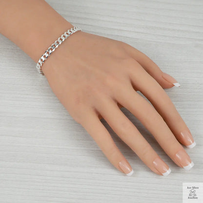 Hand wearing a silver bracelet on a light gray background