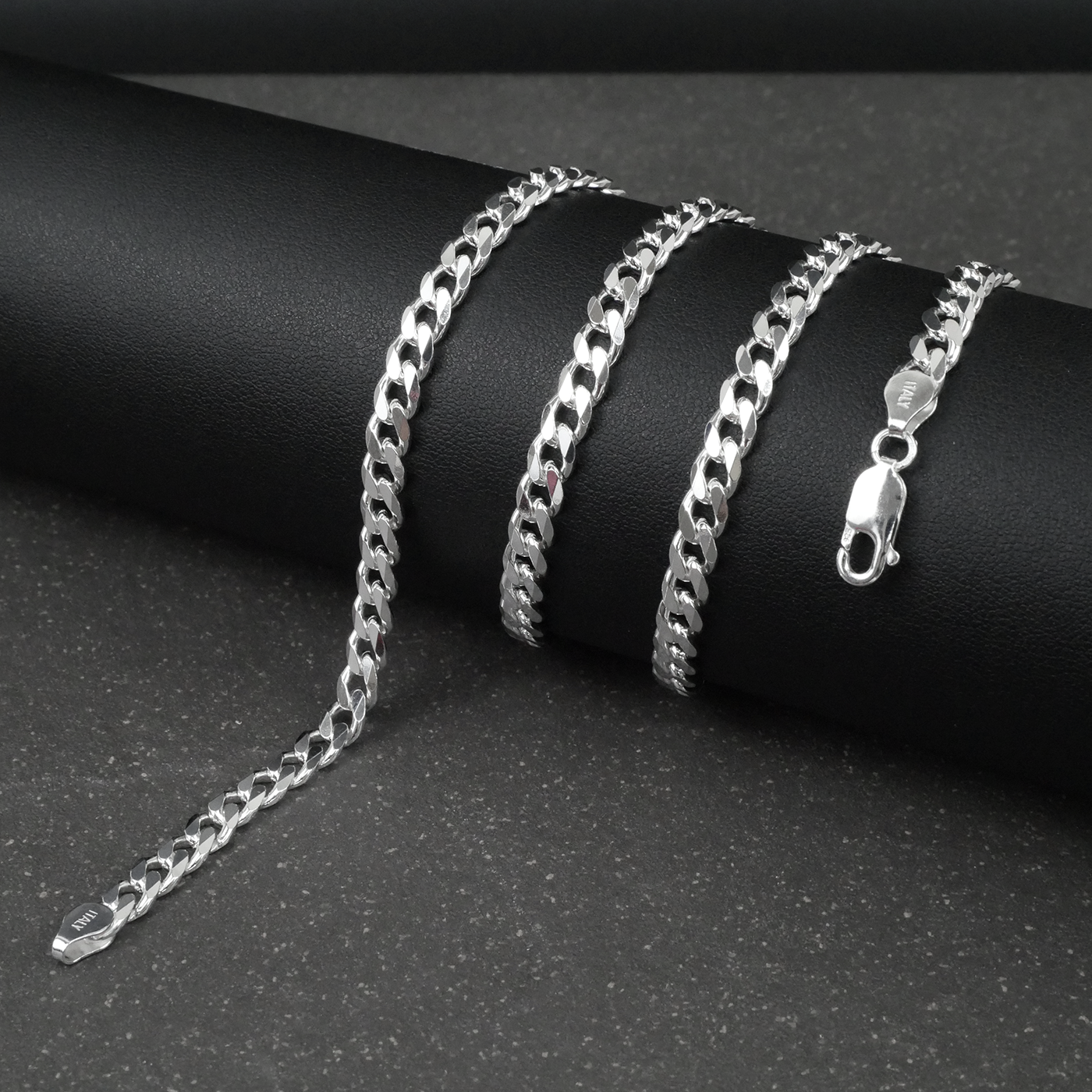 Silver curb chain on a dark surface