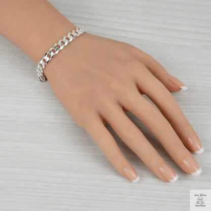 Silver chain bracelet on a hand against a neutral background