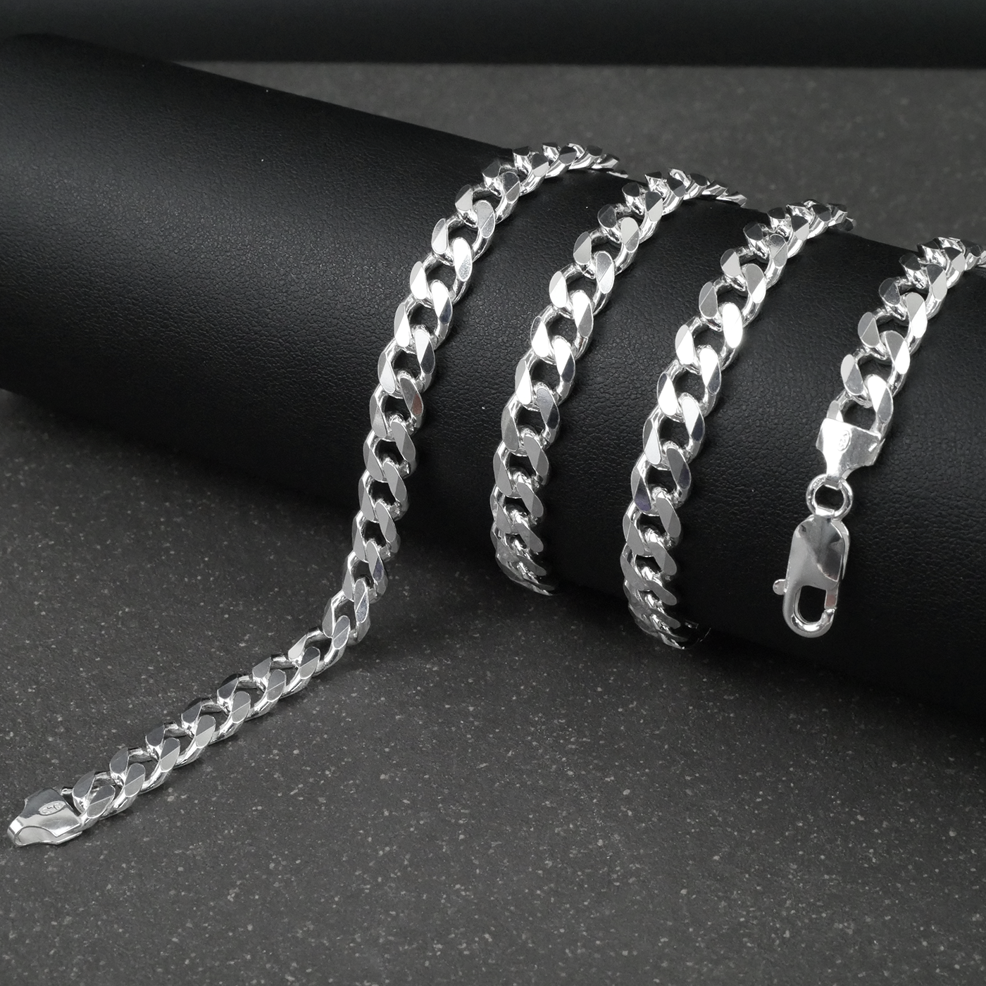 Silver curb chain on a dark surface
