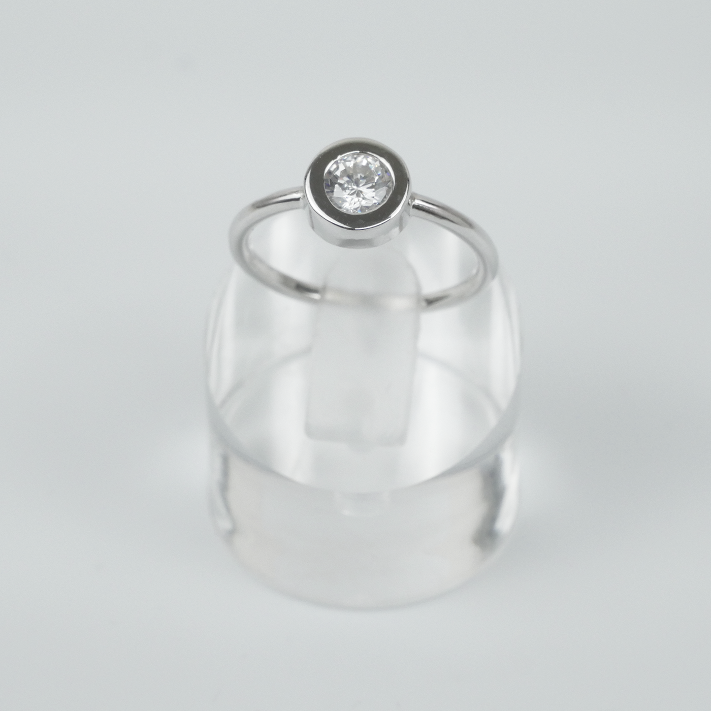Silver ring with a single CZ gemstone on a light gray background