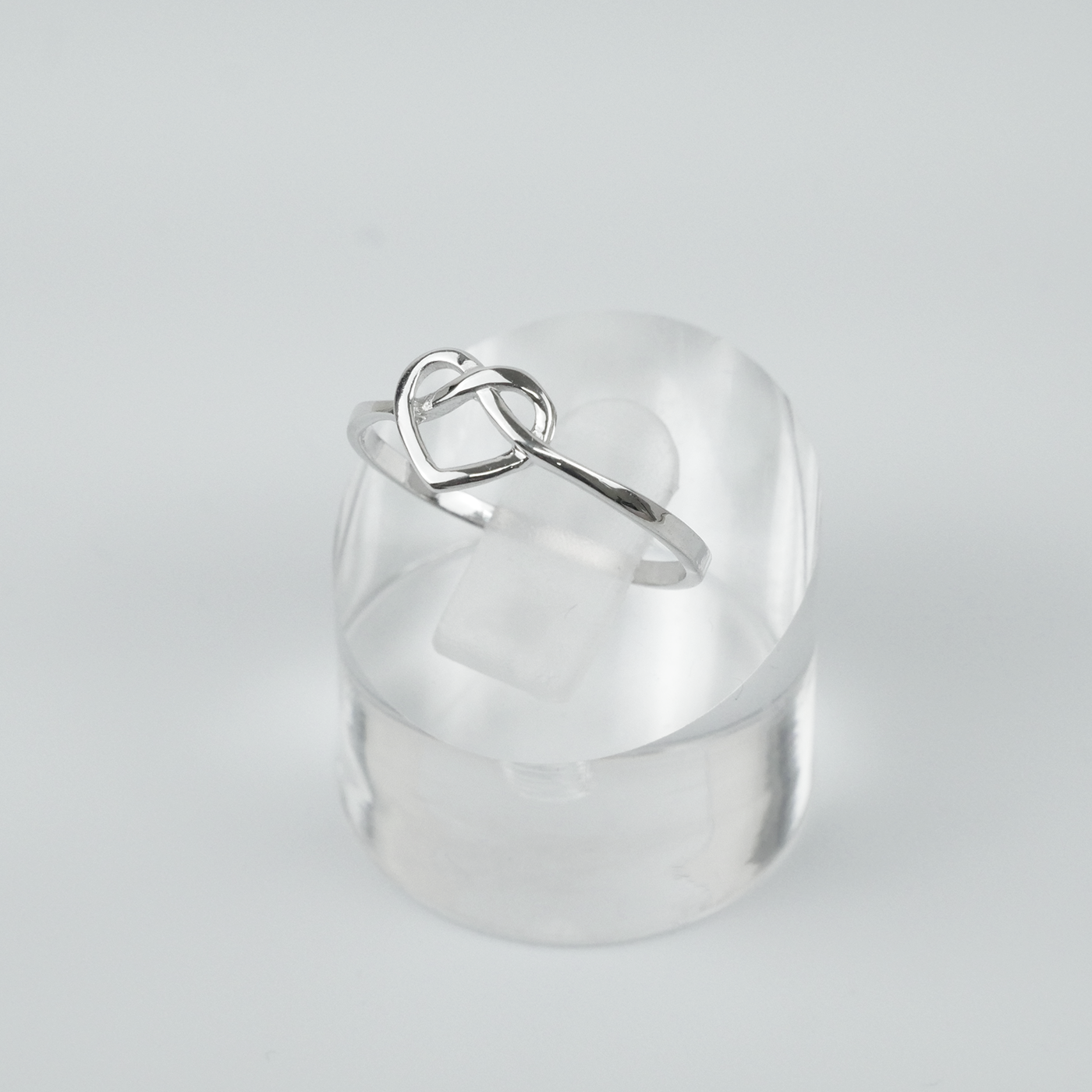 Silver ring with a heart design on a light gray background
