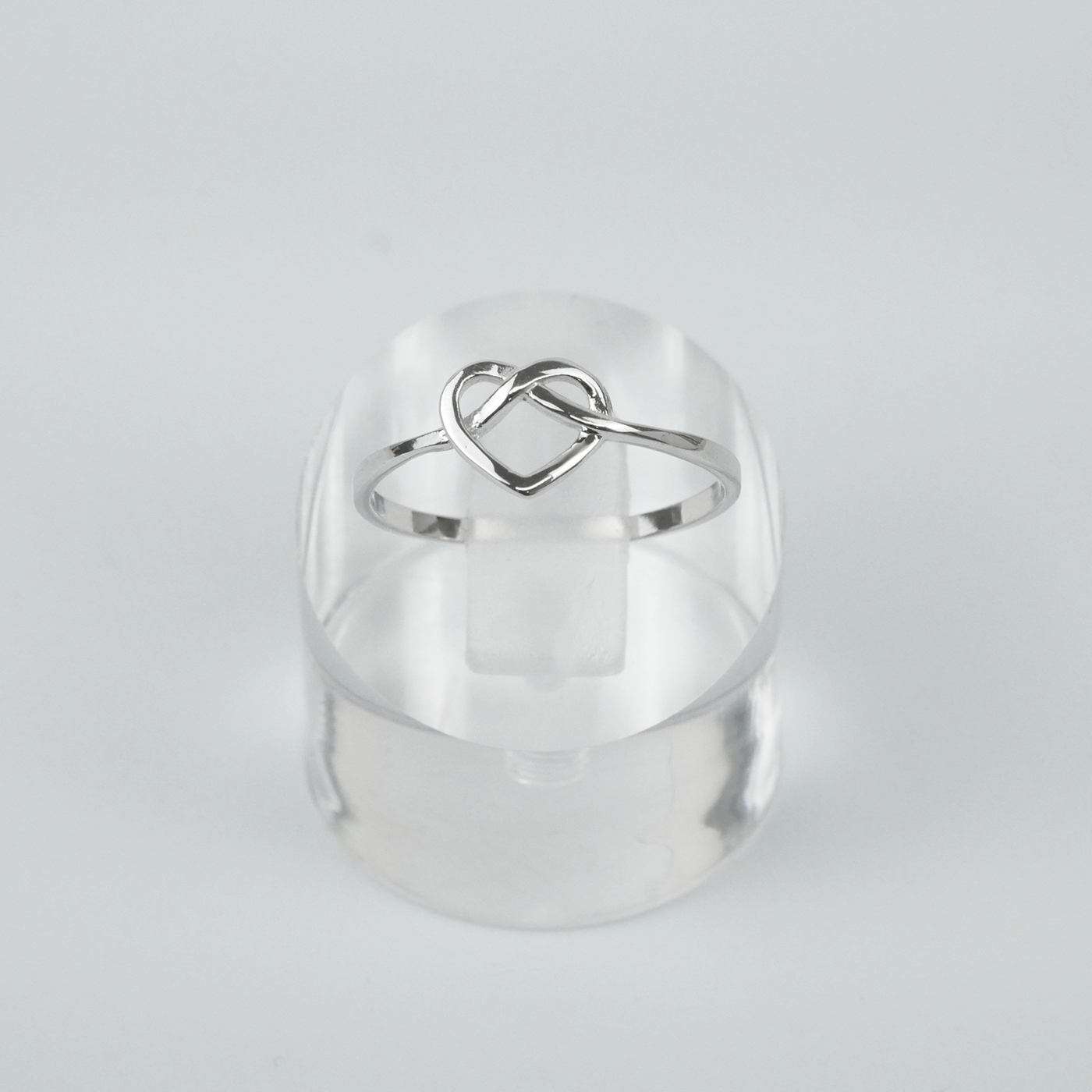 Silver ring with a heart design on a light gray background