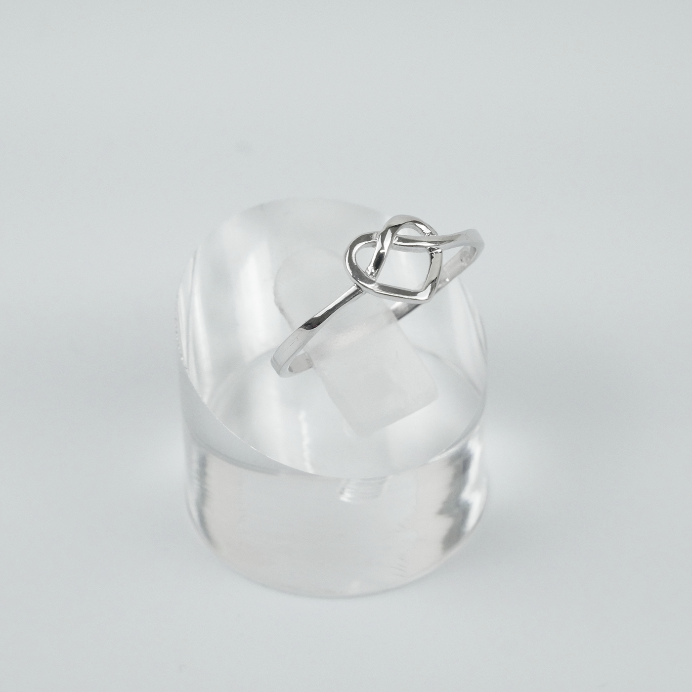 Silver ring with a heart design on a light gray background