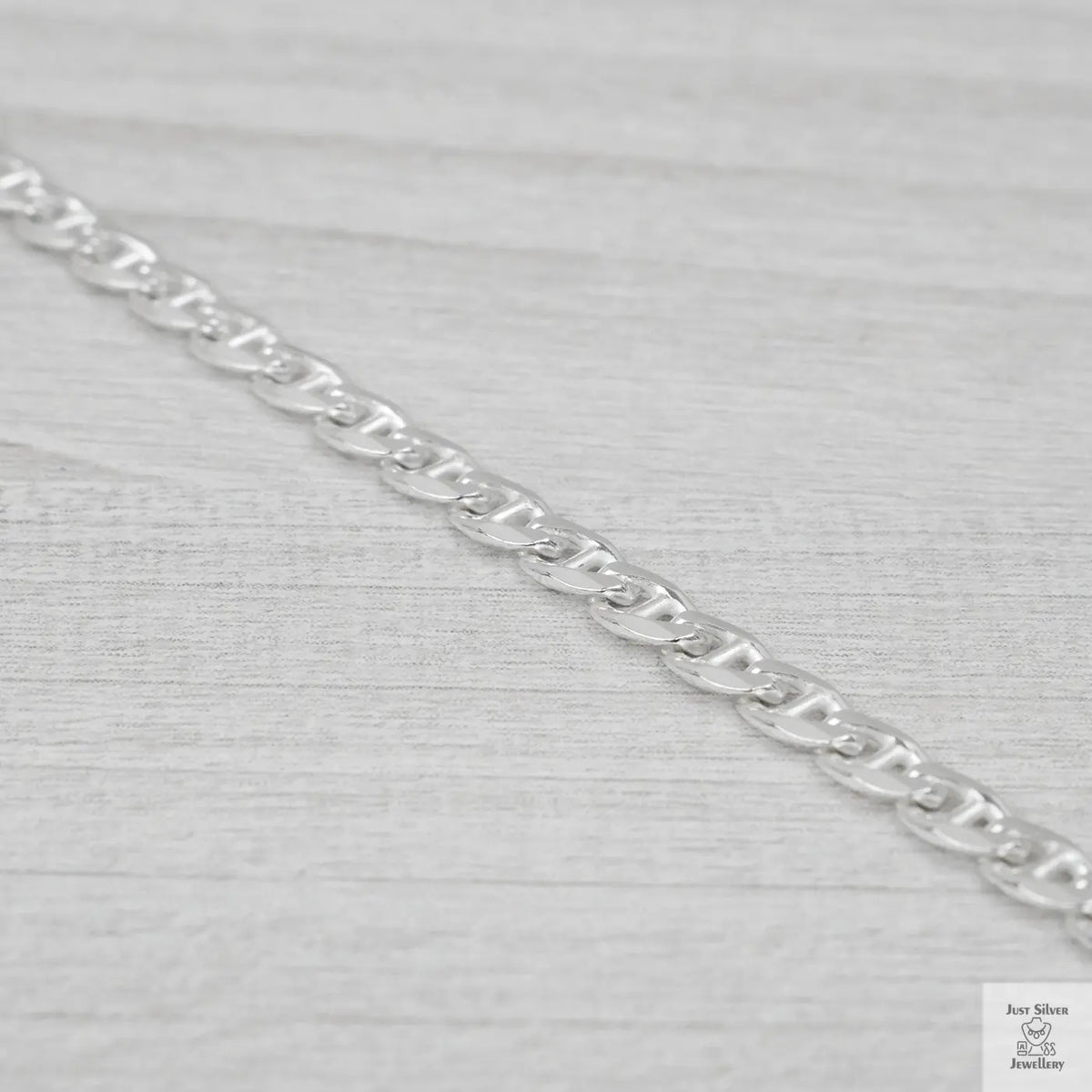 Silver marina link chain on a light grey fabric background