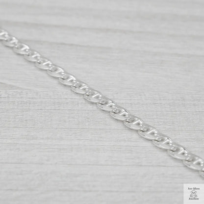 Silver marina link chain on a light grey fabric background