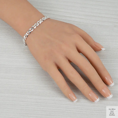 Hand wearing a silver bracelet on a light gray background