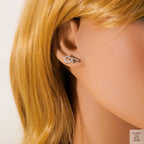Close-up of an ear wearing a heart-shaped earring with blonde hair.