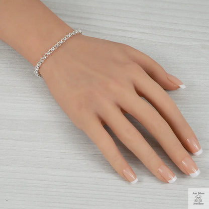 Hand wearing a silver bracelet on a light gray background