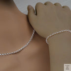 Silver Belcher/Rolo necklace and bracelet on a person's neck and wrist against a neutral background