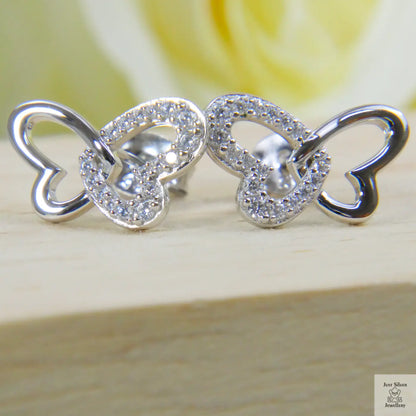 Silver butterfly-shaped earrings on a wooden surface with a blurred yellow flower in the background