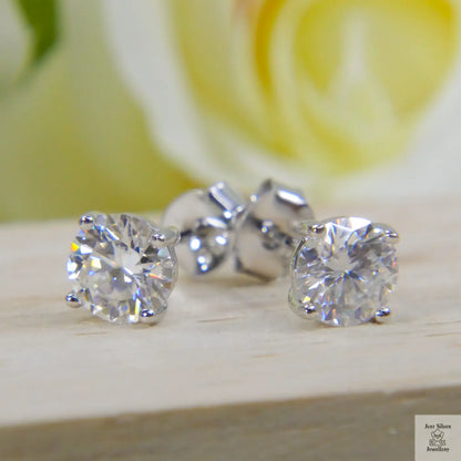 Natural Zircon stud earrings on a wooden surface with a blurred yellow flower in the background