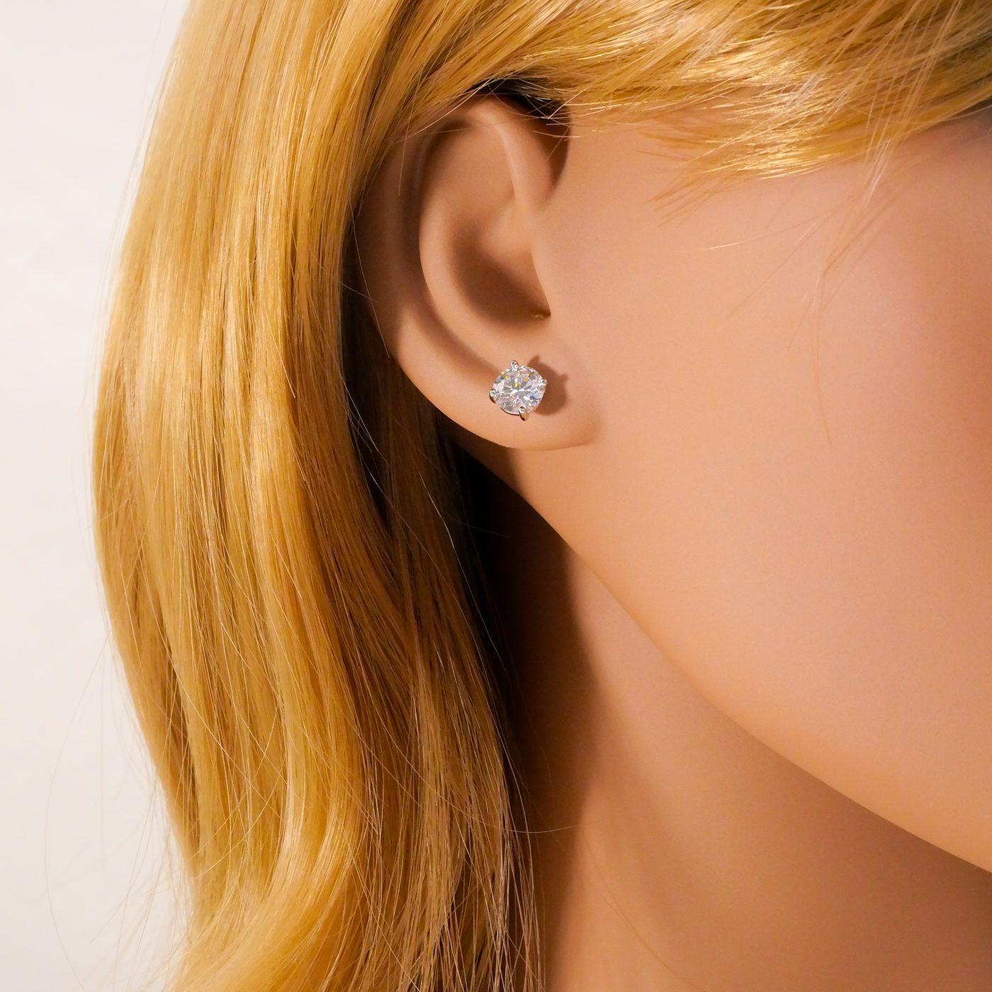 Close-up of an ear wearing a natural zircon stud earring with blonde hair.