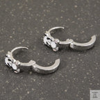Pair of silver claw-shaped earrings on a gray surface