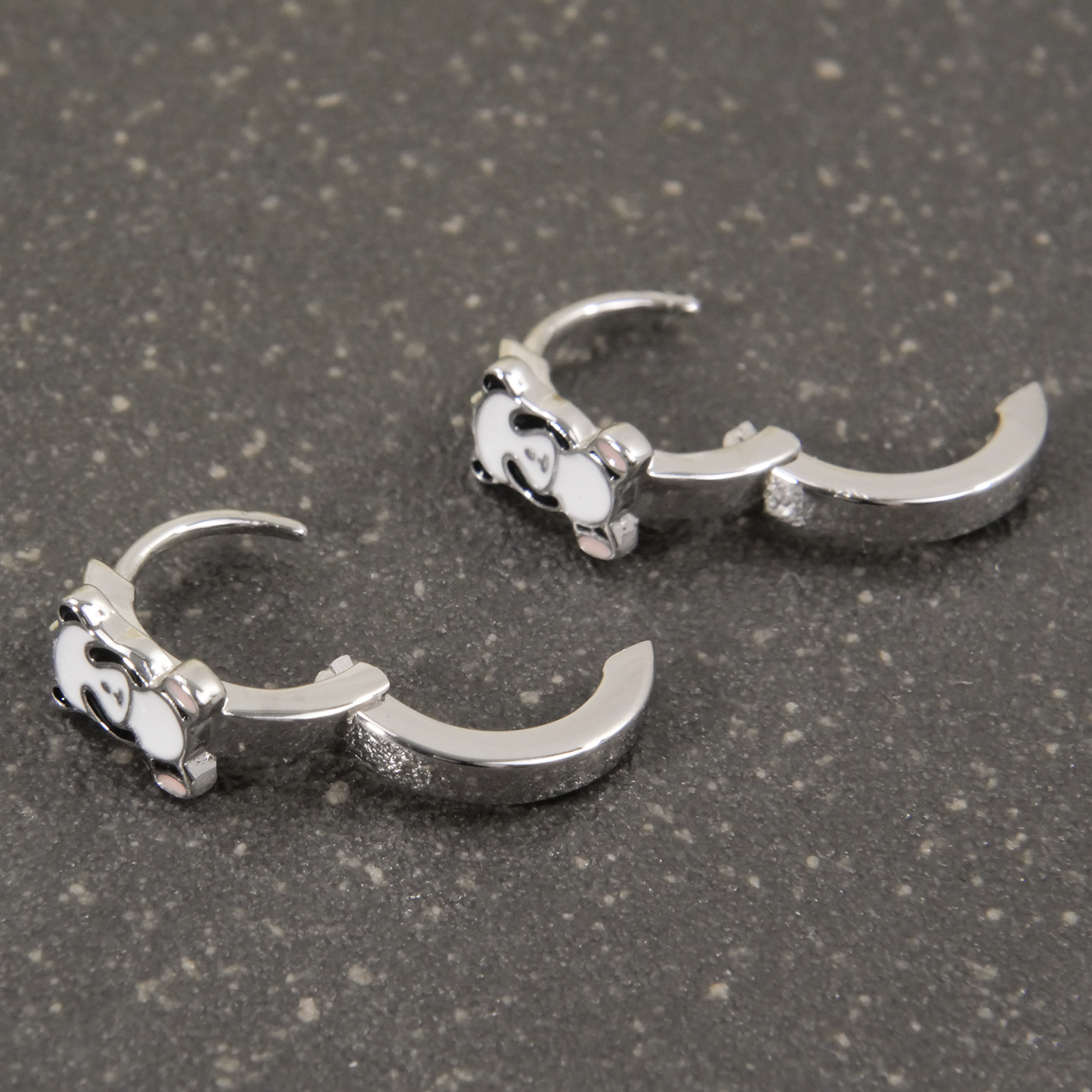 Pair of silver claw-shaped earrings on a gray surface