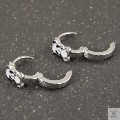 Pair of silver claw-shaped earrings on a gray surface