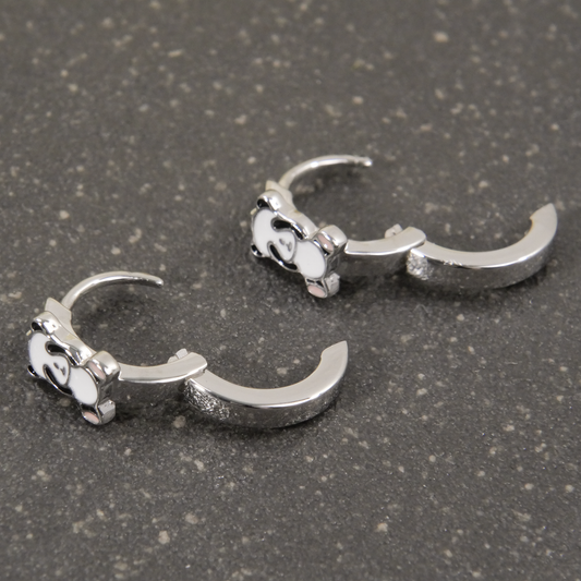 Pair of silver claw-shaped earrings on a gray surface