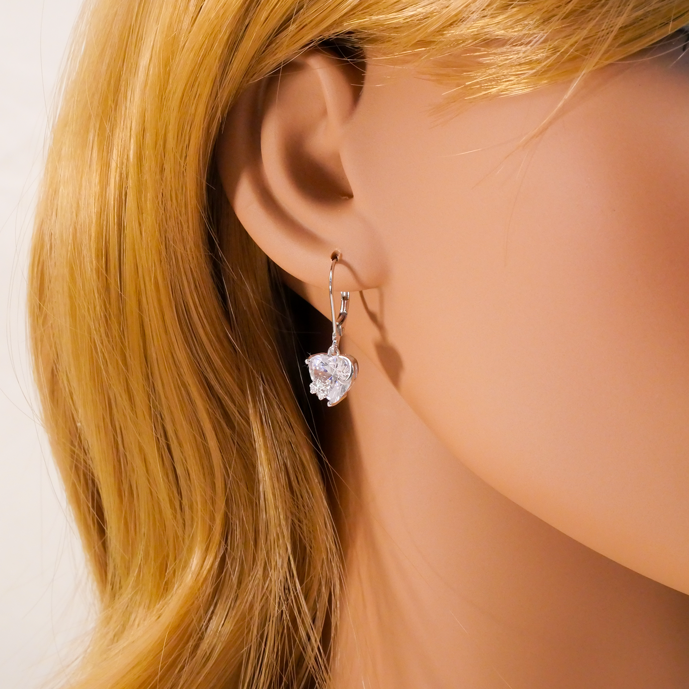 Close-up of a person wearing a heart-shaped earring with blonde hair.