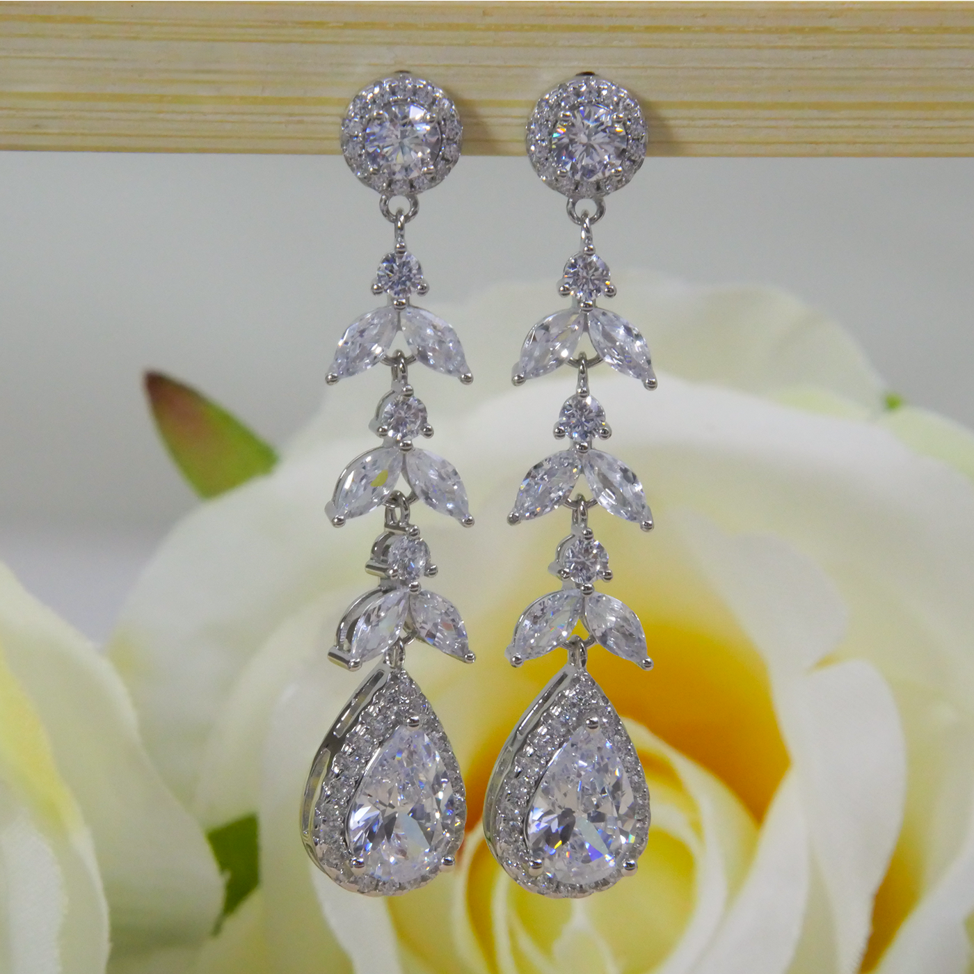 Silver earrings with clear natural zircon gemstones on a white flower background